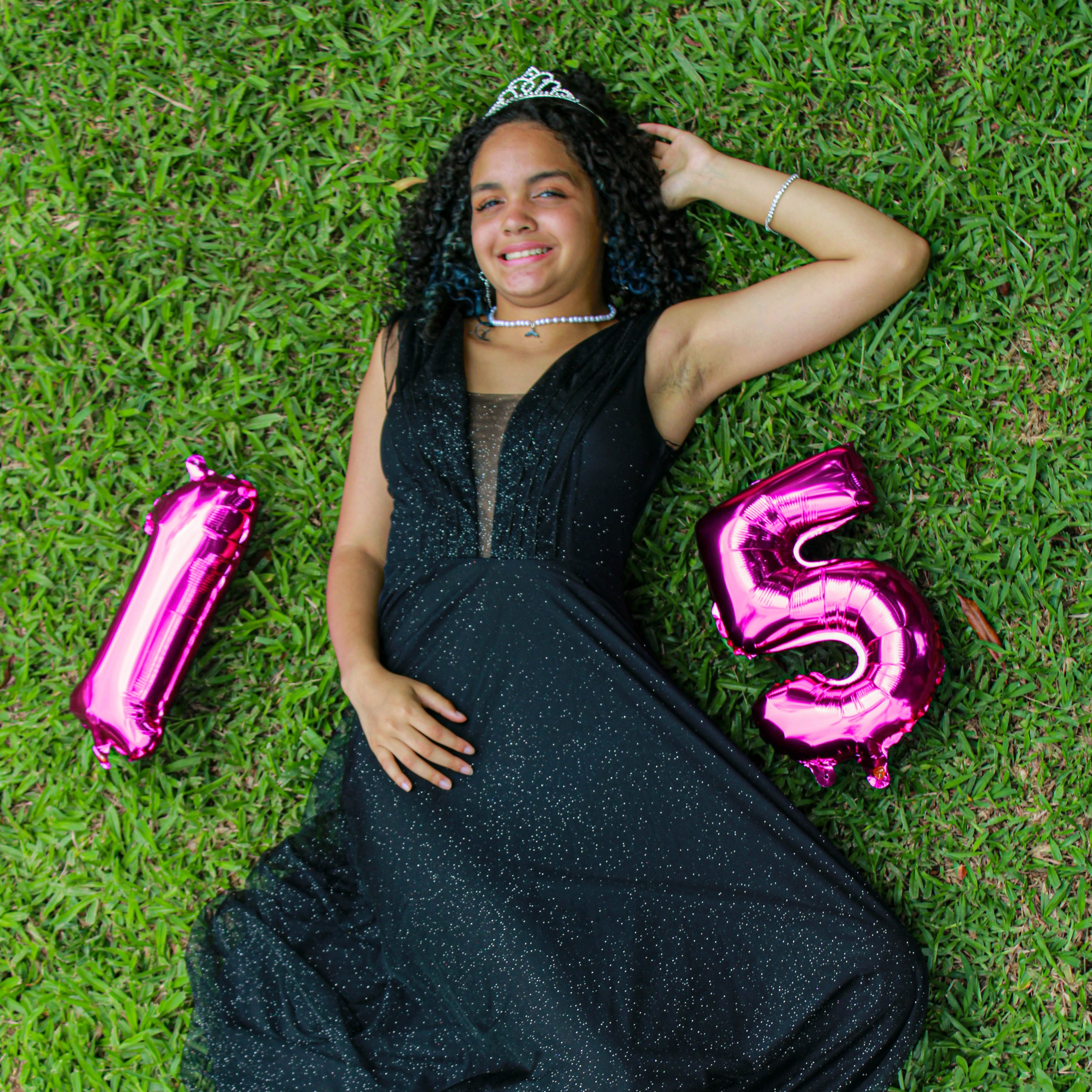 menina deitada na grama com balão de 15 anos